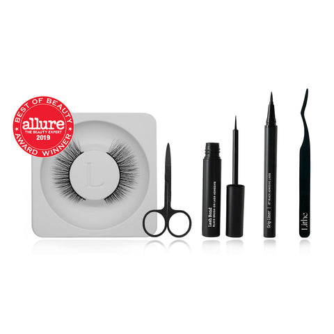 Lithe Lashes false lashes accessory, the Lithe Lash Scissors. A product image showing the Allure best of beauty seal hovering on the upper left of a pair of Core Collection lashes, and next to the lashes from left to right are the matte black Lithe Scissors, Lash Bond, Grip Liner, and Pro Lash Applicator, all floating on a white background.