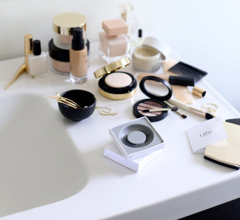 Blog_Lithe Lashes_2019 Allure Best of Beauty WINNER_Best Lashes_Featured Image_Flat lay image of opened, white lash box, showing pamphlet, and next to selective cosmetics products on a clean, white porcelain powder room sink