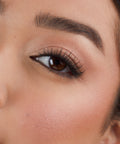 Lithe Lashes Core Collection lash style named 05 Wispy and Willowy, an image of a model’s face wearing lithe lashes on both eyes, with full makeup, looking from a left side profile, semi zoomed in, displaying the elegance of the lashes on her eyes.