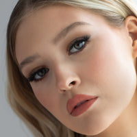 Lithe Lashes Bold Collection Style B1 - Tapered & Winged, an image of a model’s face wearing lithe lashes on both eyes, with full makeup, looking from a left side profile, semi zoomed in, displaying the elegance of the lashes on her eyes.
