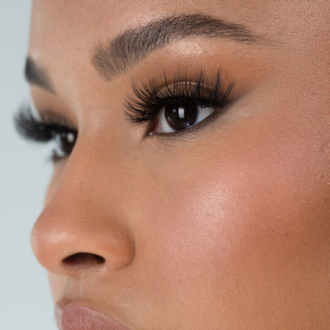 Lithe Lashes Bold Collection Style B2 - Full Flare, an image of a model’s face wearing lithe lashes on both eyes, with full makeup, looking from a left side profile, semi zoomed in, displaying the elegance of the lashes on her eyes.