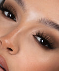 Lithe Lashes Bold Collection Style B4 - Wispy & Bold, an image of a model’s face wearing lithe lashes on both eyes, with full makeup, looking from a left side profile, semi zoomed in, displaying the elegance of the lashes on her eyes.