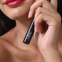Lithe Lashes false lashes accessories lash bond lash adhesive, waterproof and free of latex, parabens, phthalates, and formaldehyde. The image shows a model holding the glue bottle in her left hand, showing the bottom half of the matte black bottle highlighting the Lithe logo on it